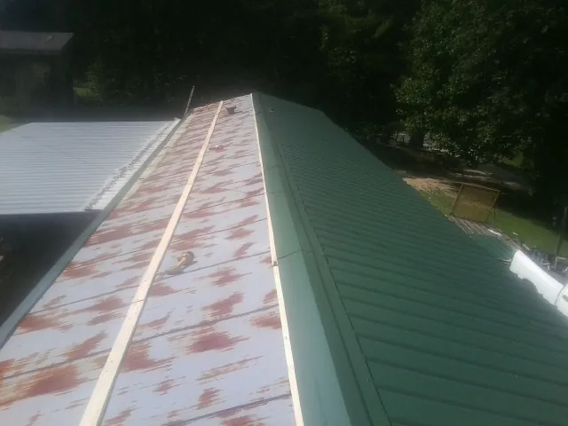 Old rusted panels beside newly installed green metal roofing — Wind Damage Roof Repair by Roofing Brothers in Teaneck