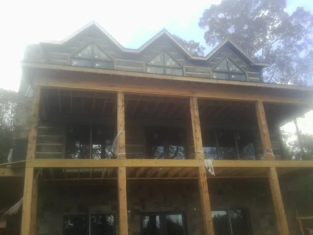 Dormers and porch framing on a large log home under construction — Roof Coating work by our crew in Teaneck