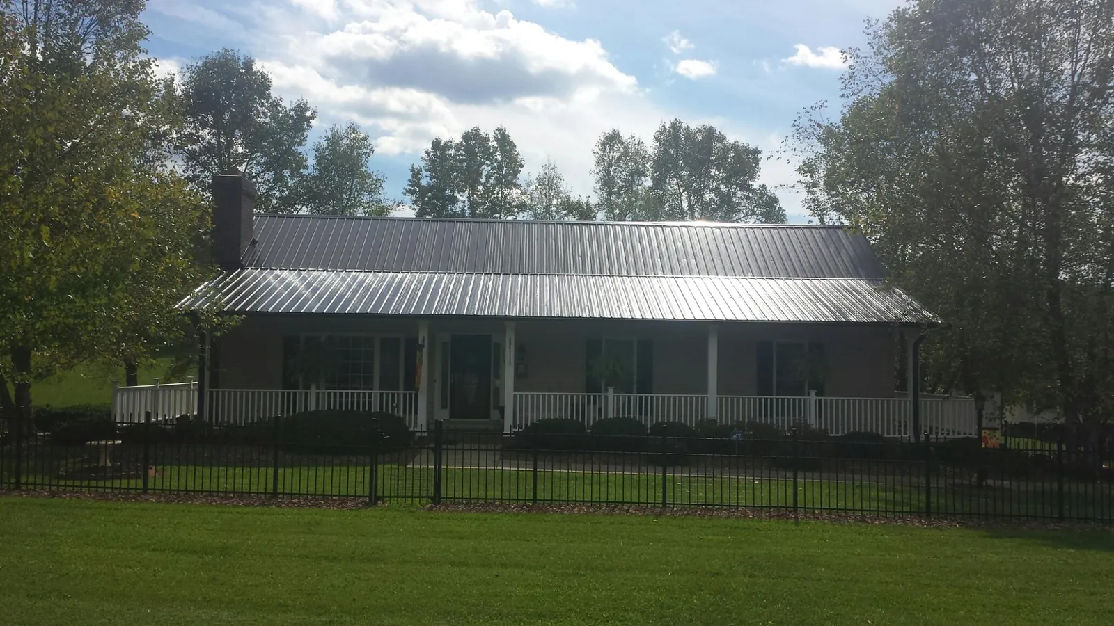 Gray metal roof on a brick ranch with a full width front porch — Gutter Guard Installation work by our crew in Teaneck