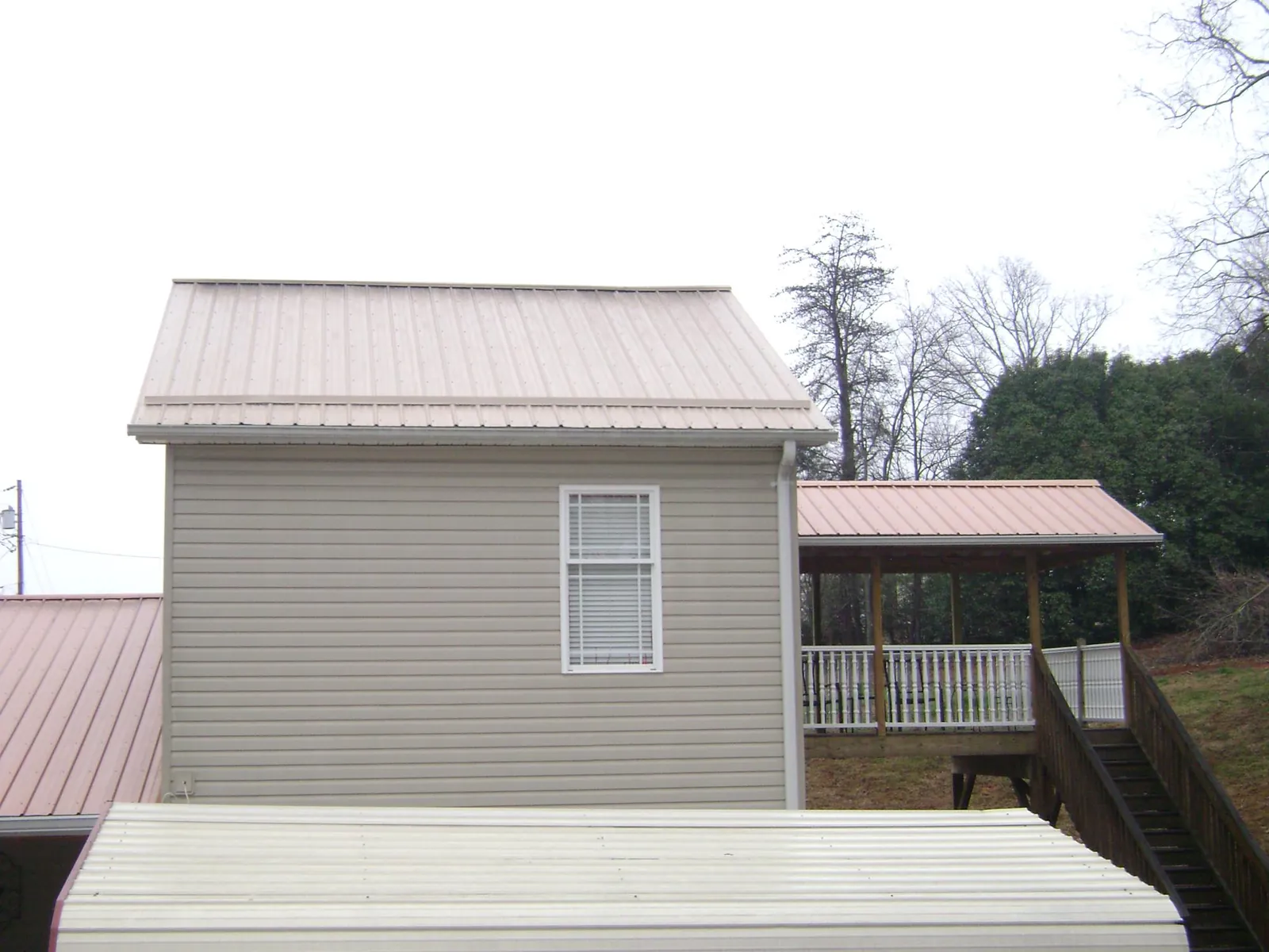 Tan metal roofs on a two story addition and attached porch, from a Roof Replacement job in Teaneck