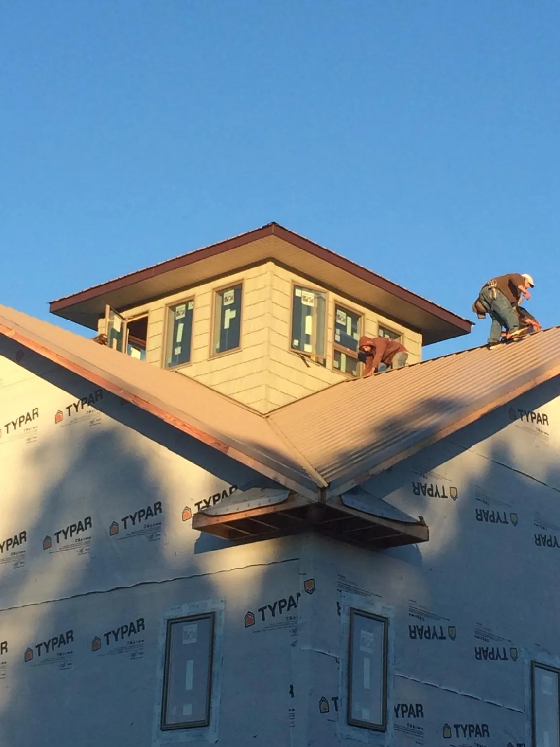 Roofers working around a rooftop cupola on a new metal roof at sunset — Roof Waterproofing in Teaneck by Roofing Brothers